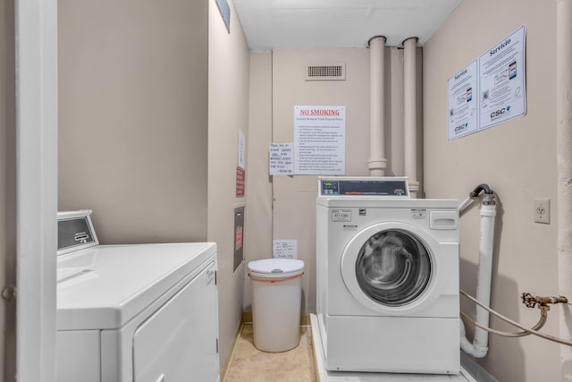 clothes washing area featuring light tile patterned floors and washing machine and clothes dryer