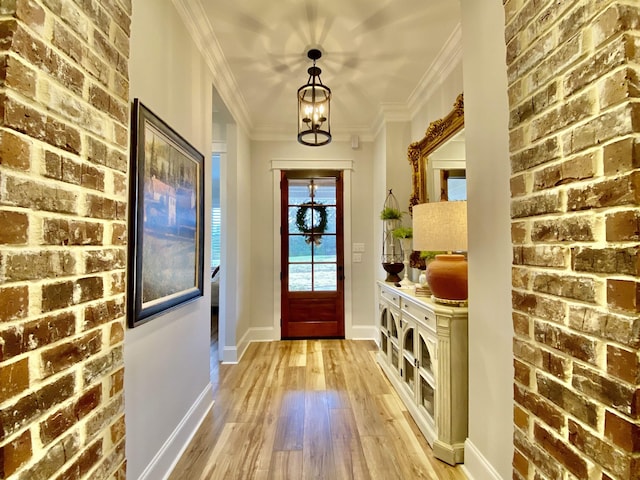 interior space with a notable chandelier, ornamental molding, and light hardwood / wood-style flooring