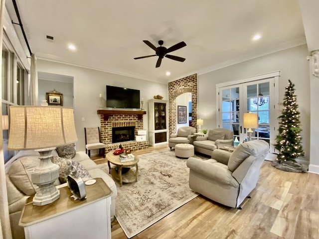 living room featuring light hardwood / wood-style floors, a brick fireplace, ceiling fan, and ornamental molding