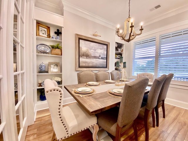 dining area with a notable chandelier, built in features, ornamental molding, and light hardwood / wood-style flooring