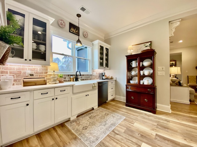 kitchen featuring pendant lighting, backsplash, black dishwasher, light hardwood / wood-style floors, and white cabinetry