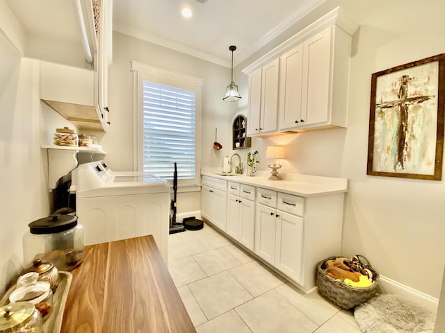 washroom featuring washer and clothes dryer, cabinets, sink, ornamental molding, and light tile patterned floors