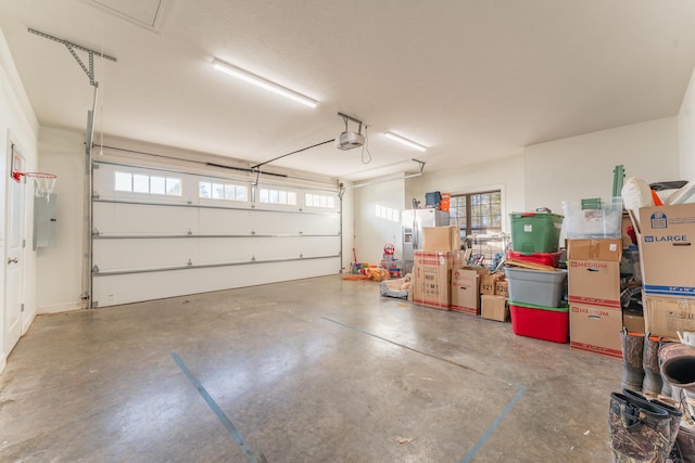 garage featuring electric panel, stainless steel refrigerator with ice dispenser, and a garage door opener