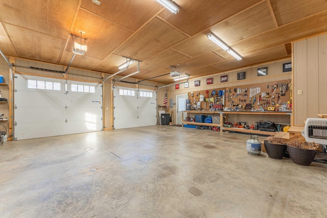 garage featuring heating unit, a workshop area, and wood ceiling