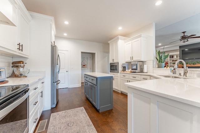 kitchen with white cabinets, a kitchen island, stainless steel appliances, sink, and backsplash