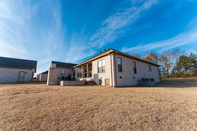 back of property featuring a lawn and central AC