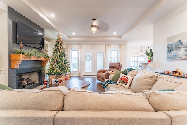 living room featuring wood-type flooring, a fireplace, and a tray ceiling