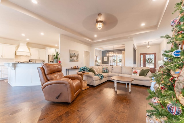 living room with a tray ceiling, dark hardwood / wood-style flooring, and an inviting chandelier