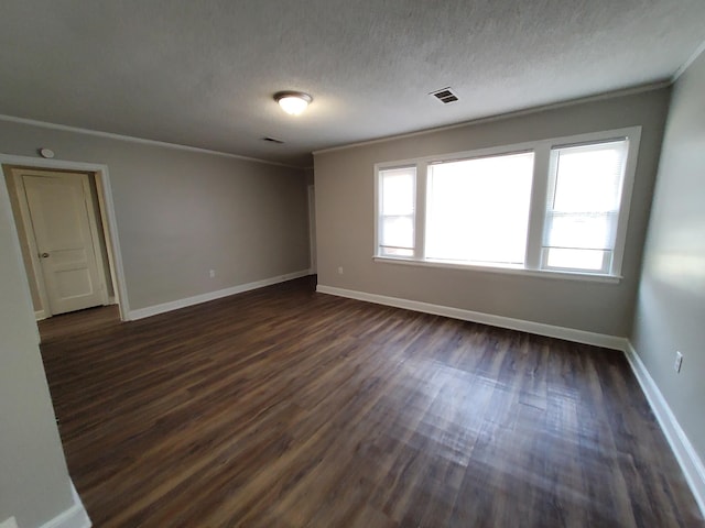 empty room featuring a textured ceiling, crown molding, and dark wood-type flooring