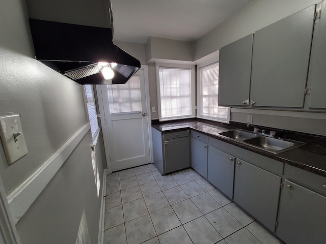 kitchen featuring light tile patterned flooring, gray cabinets, extractor fan, and sink