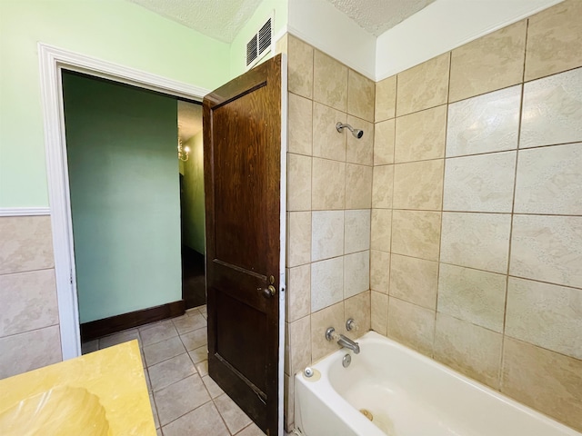 bathroom with tile patterned flooring, a textured ceiling, and tiled shower / bath