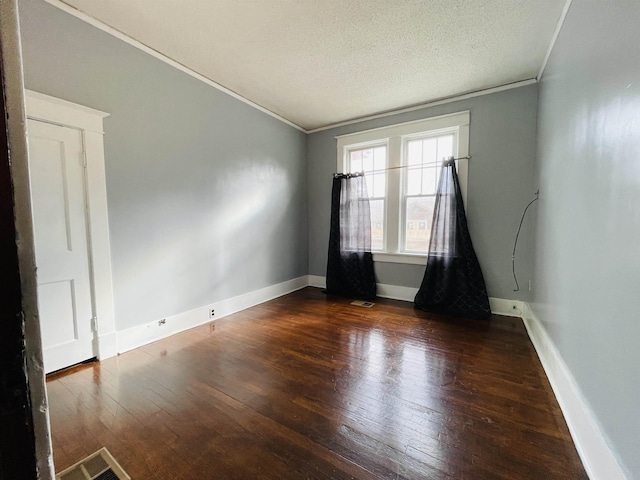 unfurnished room featuring a textured ceiling, dark hardwood / wood-style flooring, and ornamental molding