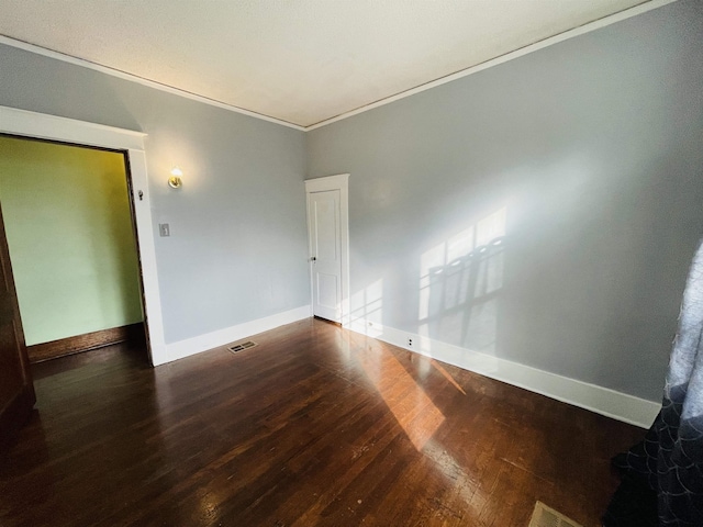 spare room with dark hardwood / wood-style flooring and crown molding