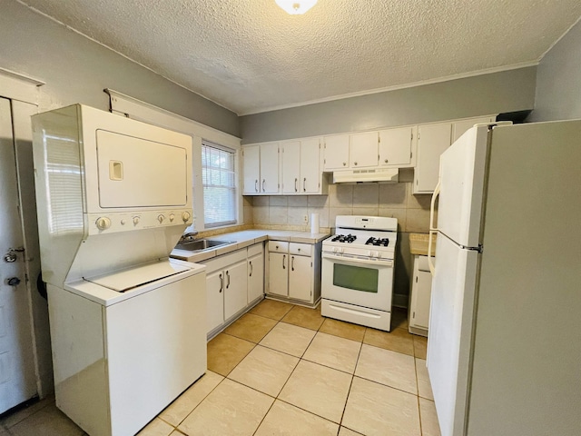 kitchen with white cabinets, stacked washer and dryer, white appliances, and tasteful backsplash