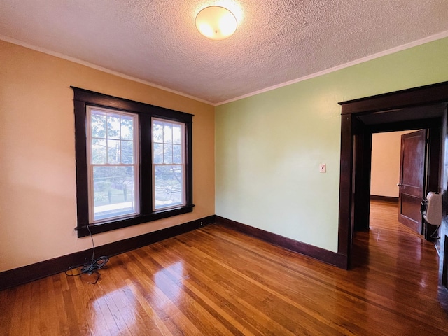 empty room with wood-type flooring, a textured ceiling, and ornamental molding