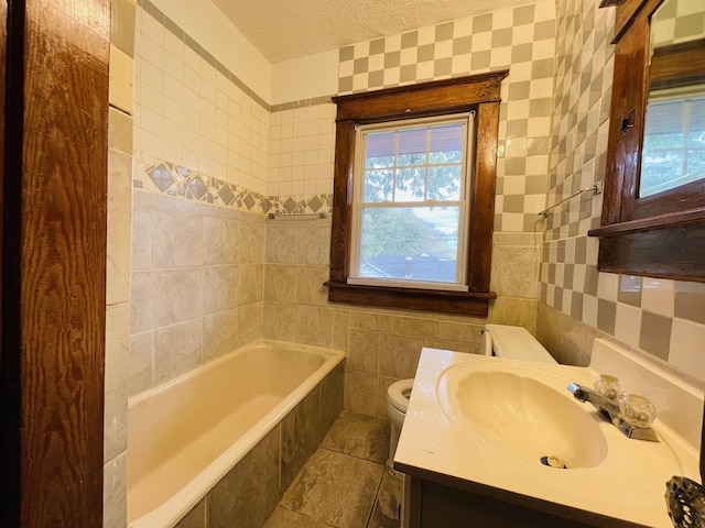 bathroom with vanity, a bath, toilet, a textured ceiling, and tile walls