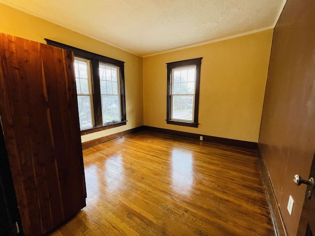 unfurnished room with hardwood / wood-style floors, crown molding, and a textured ceiling