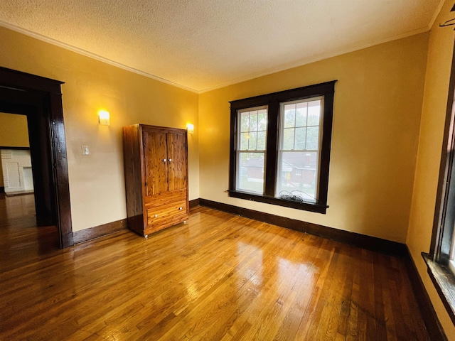 unfurnished bedroom featuring hardwood / wood-style floors, a textured ceiling, and ornamental molding