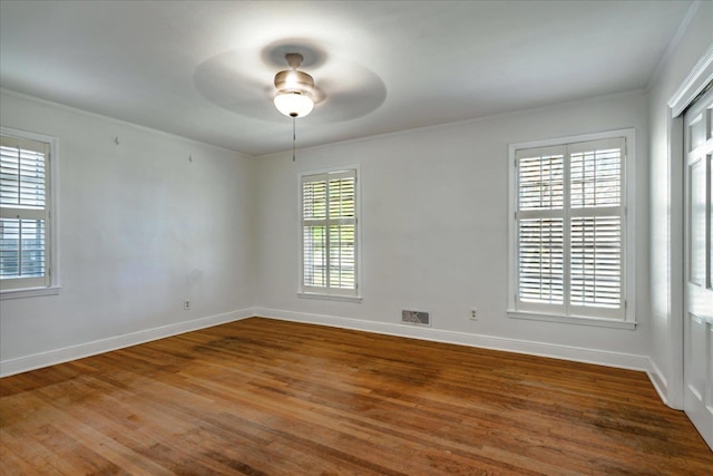 spare room with ceiling fan, wood-type flooring, ornamental molding, and a wealth of natural light