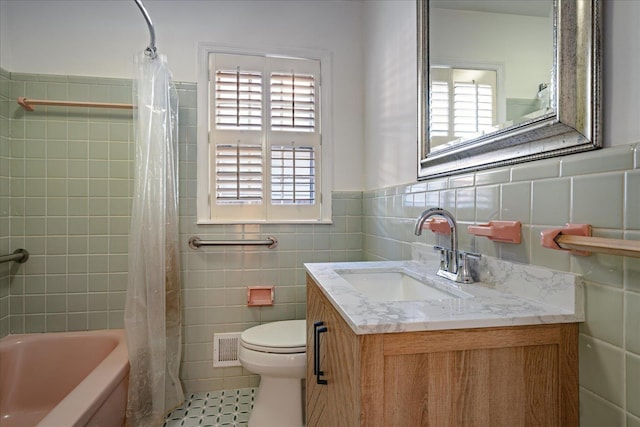 full bathroom with tile patterned floors, vanity, a healthy amount of sunlight, and tile walls