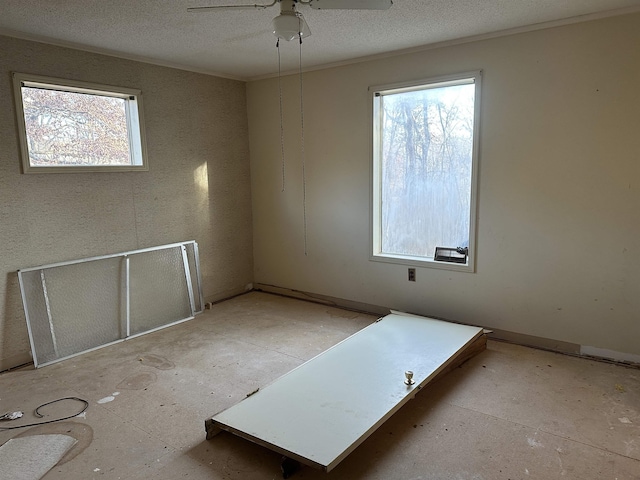 unfurnished room featuring ceiling fan, a textured ceiling, and a wealth of natural light