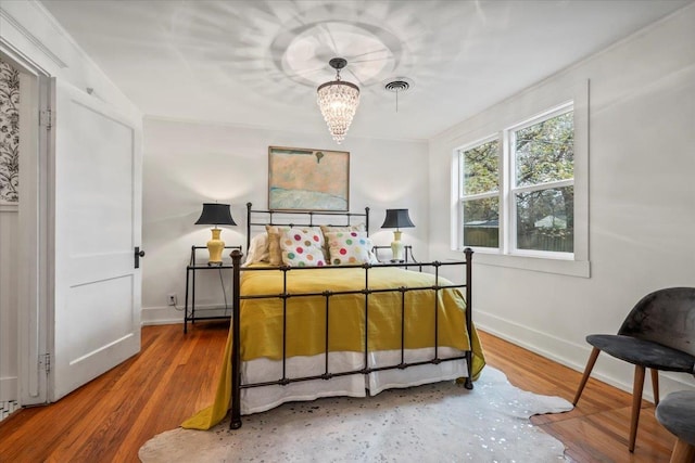 bedroom with hardwood / wood-style floors and an inviting chandelier