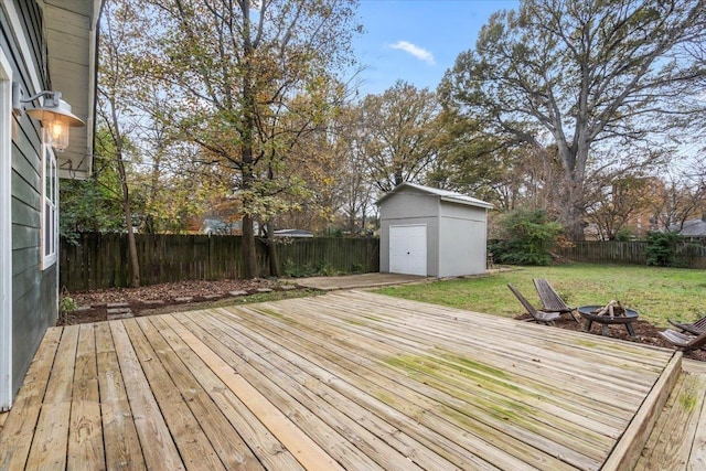 wooden terrace with a shed, a yard, and a fire pit