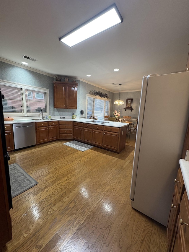 kitchen with sink, stainless steel dishwasher, white refrigerator, decorative light fixtures, and light wood-type flooring