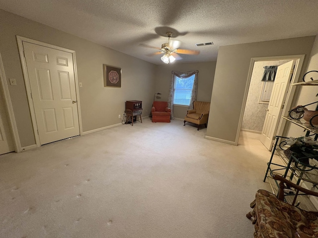 sitting room featuring light carpet, ceiling fan, and a textured ceiling