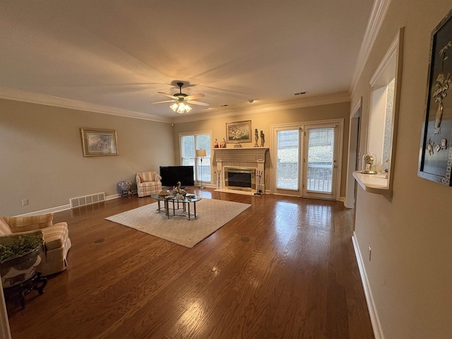 living room with a tile fireplace, dark hardwood / wood-style flooring, ceiling fan, and ornamental molding