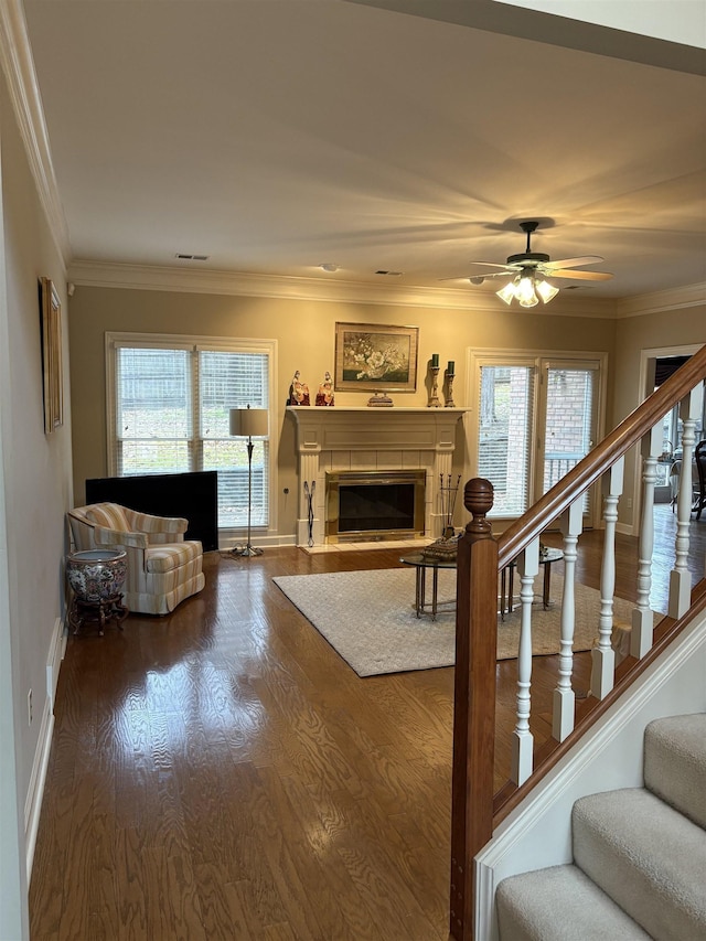 living room with a tile fireplace, crown molding, and plenty of natural light