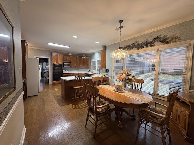 dining area with hardwood / wood-style floors, a notable chandelier, and ornamental molding