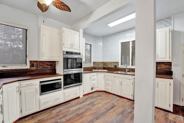 kitchen with hardwood / wood-style floors, appliances with stainless steel finishes, white cabinets, and sink