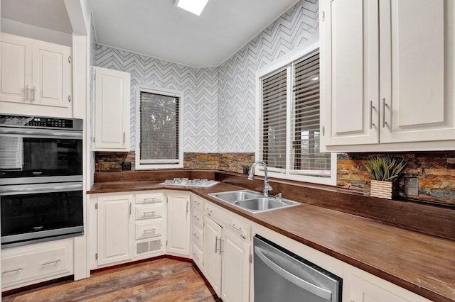 kitchen featuring hardwood / wood-style flooring, sink, white cabinets, and appliances with stainless steel finishes