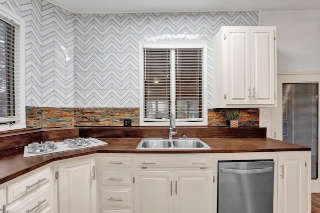 kitchen with white cabinets, stainless steel dishwasher, and sink