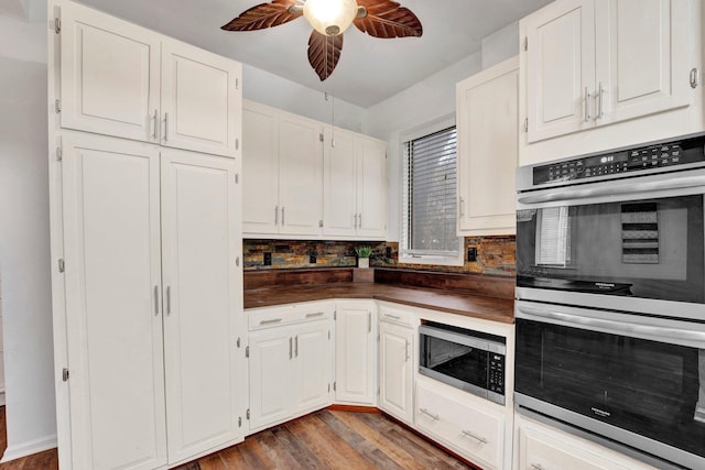 kitchen with tasteful backsplash, white cabinetry, stainless steel appliances, and dark wood-type flooring