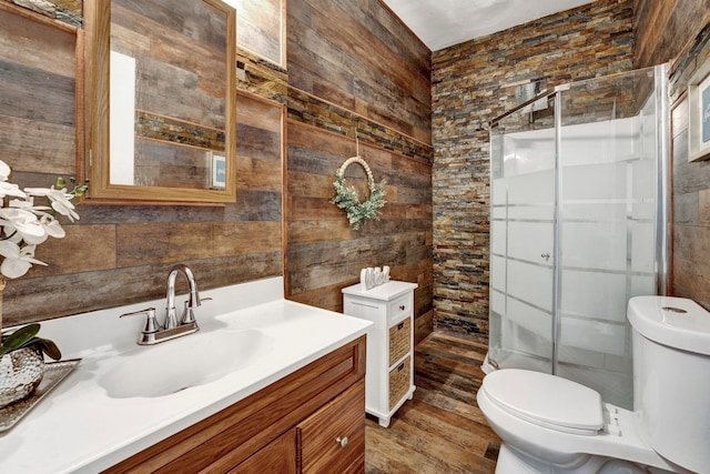 bathroom featuring walk in shower, vanity, wood-type flooring, toilet, and wood walls