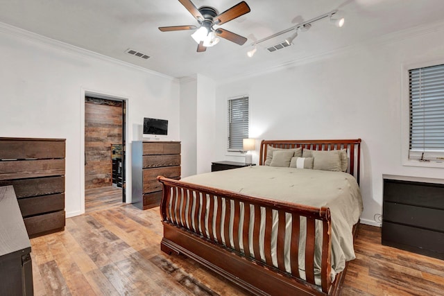 bedroom with ceiling fan, crown molding, rail lighting, and hardwood / wood-style flooring