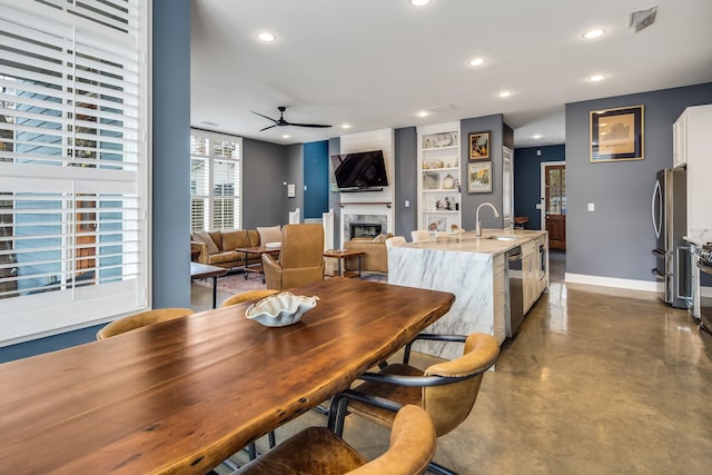 dining area with sink, built in shelves, concrete flooring, and ceiling fan