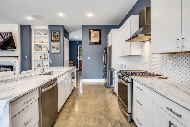 kitchen with sink, white cabinets, wall chimney exhaust hood, and appliances with stainless steel finishes