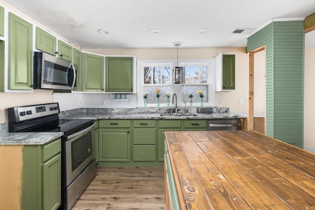 kitchen with appliances with stainless steel finishes, green cabinetry, pendant lighting, and sink