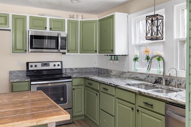 kitchen featuring green cabinets, sink, a textured ceiling, and appliances with stainless steel finishes