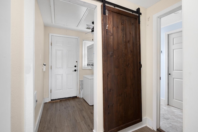 hall featuring hardwood / wood-style floors, a barn door, and separate washer and dryer