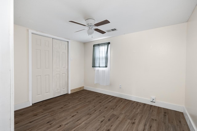 unfurnished bedroom with dark hardwood / wood-style floors, ceiling fan, and a closet