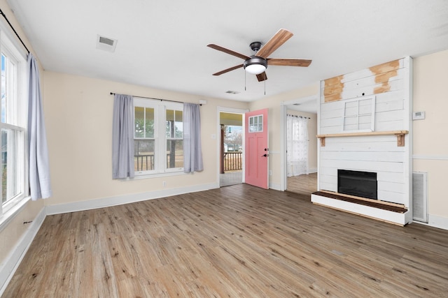 unfurnished living room featuring hardwood / wood-style floors, ceiling fan, and a fireplace