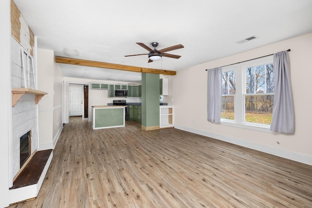 unfurnished living room featuring a fireplace, hardwood / wood-style floors, ceiling fan, and beamed ceiling