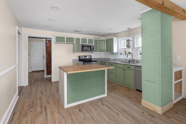 kitchen featuring a barn door, light hardwood / wood-style flooring, decorative light fixtures, and appliances with stainless steel finishes