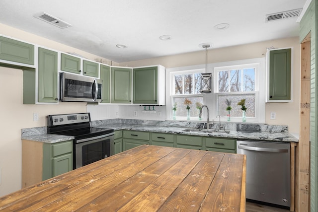 kitchen with sink, decorative light fixtures, green cabinetry, and appliances with stainless steel finishes