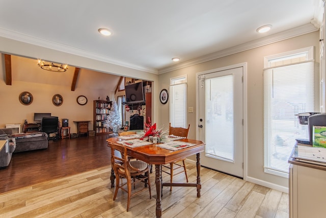 dining space with a fireplace, beamed ceiling, light wood-type flooring, and ornamental molding