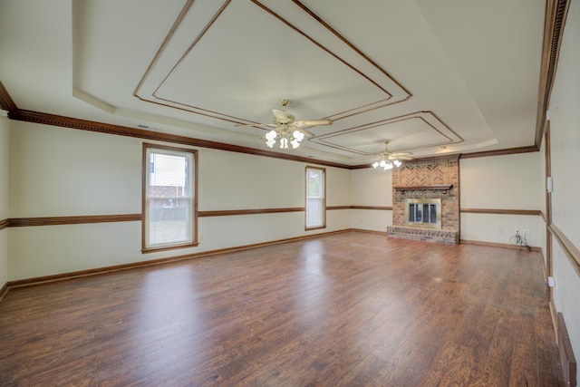 unfurnished living room with ceiling fan, a raised ceiling, dark hardwood / wood-style flooring, crown molding, and a fireplace